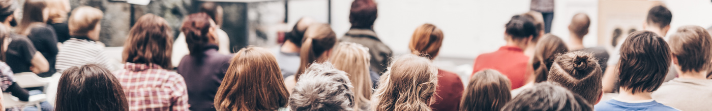 An image taken from the back of a lecture room with people sitting in chairs