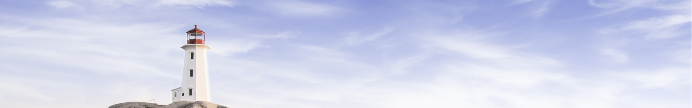 A landscape image of a lighthouse on a rocky point with blue skies